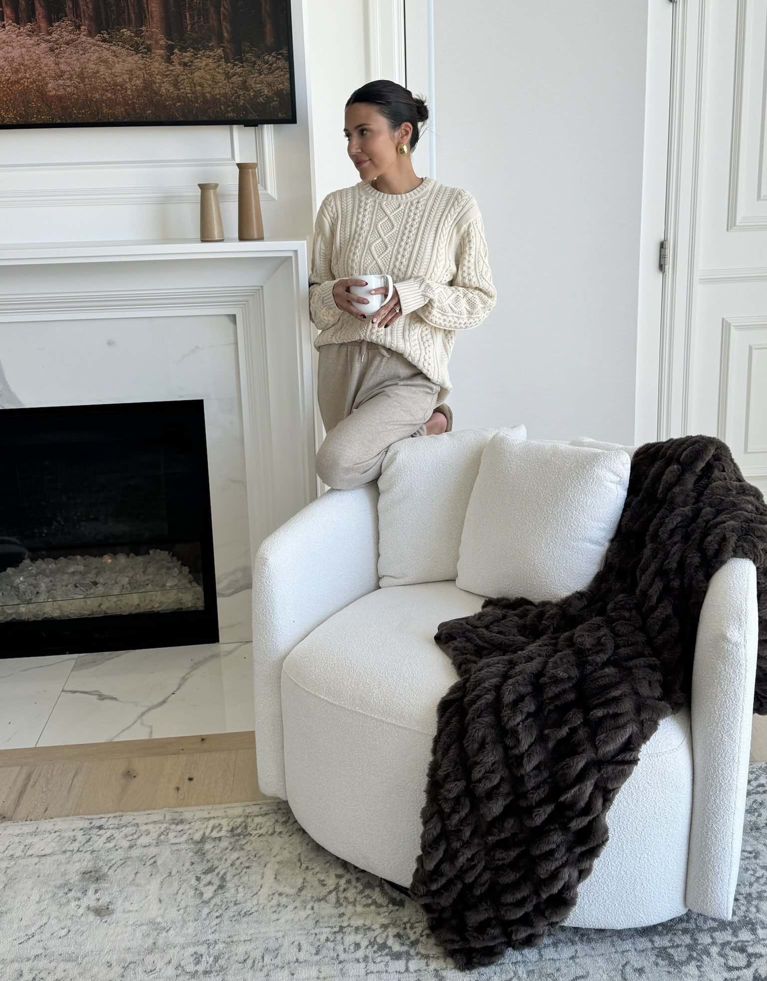 Christine Andrew at home in her primary bedroom with her white accent swivel chair.