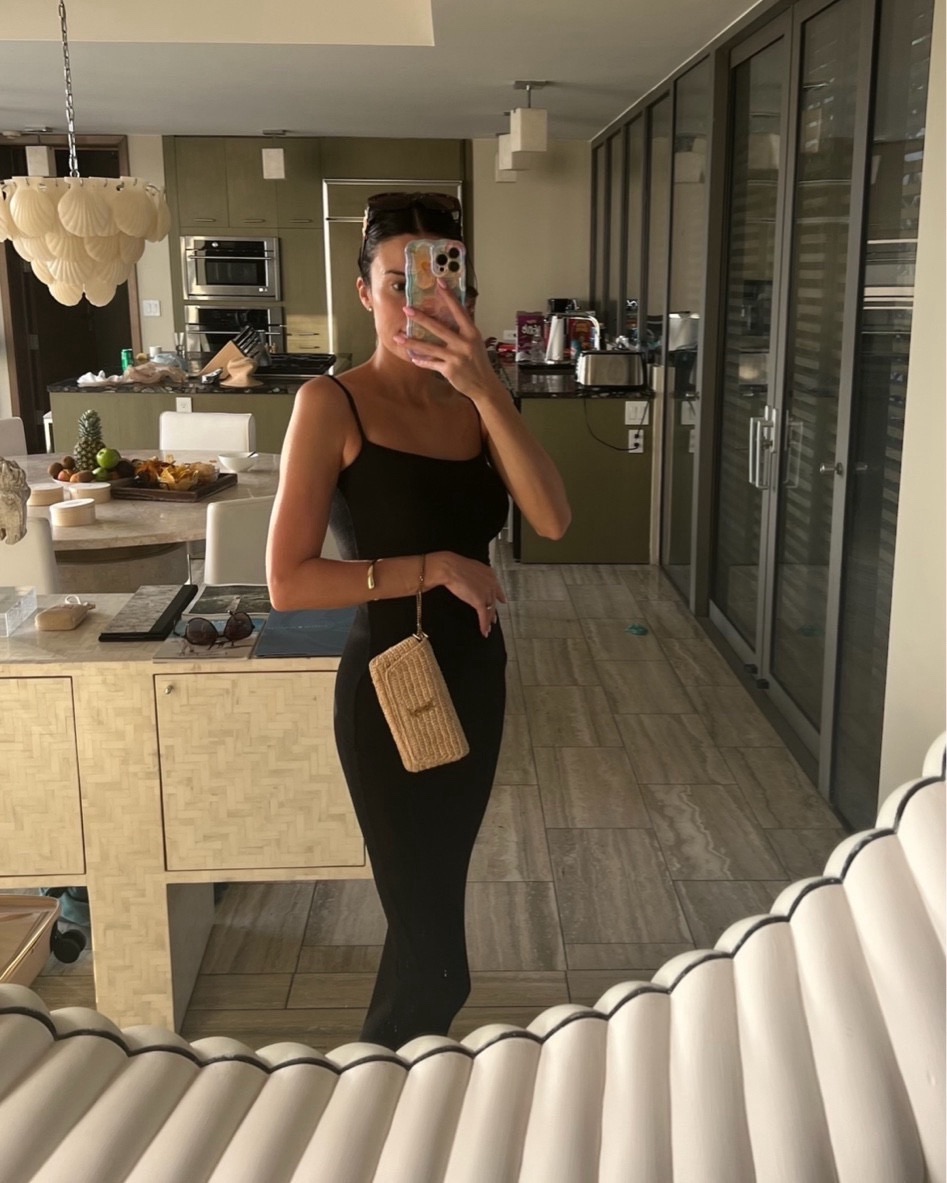 Christine Andrew in a long black skims dress on a beach vacation